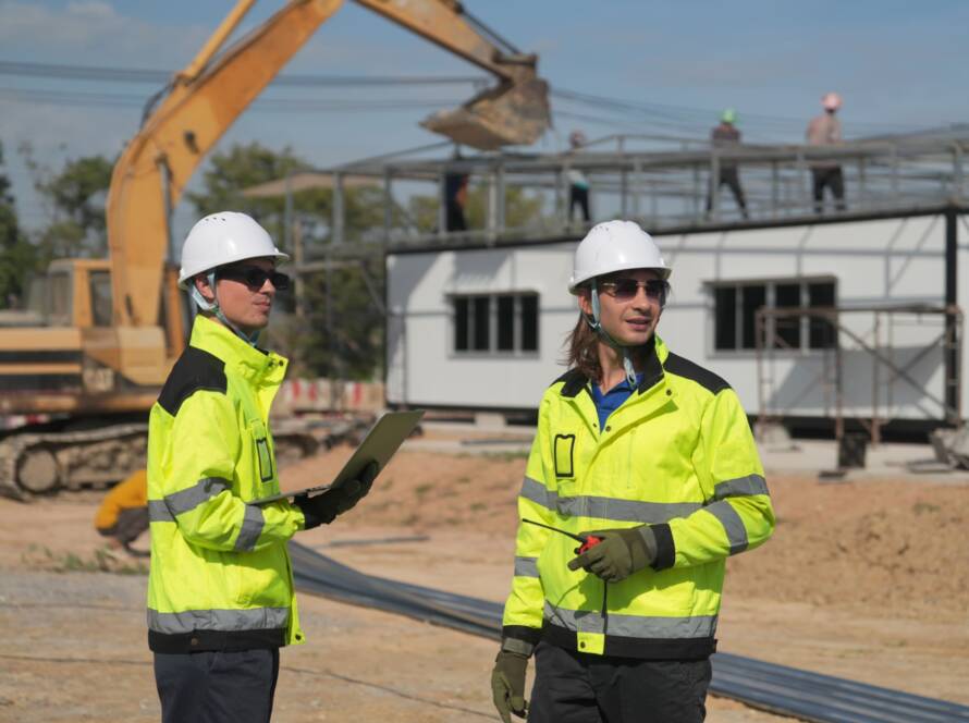 construction-workers-discuss-plans-at-a-building-s-2026-03-18-05-37-52-utc